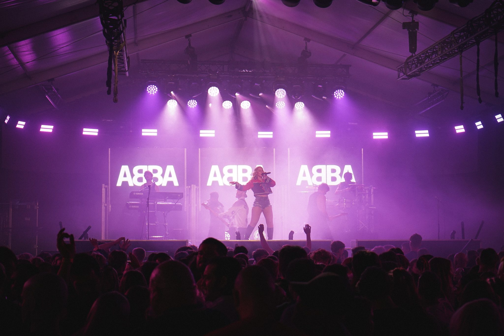 Podium met ABBA op de schermen en een volle festivaltent